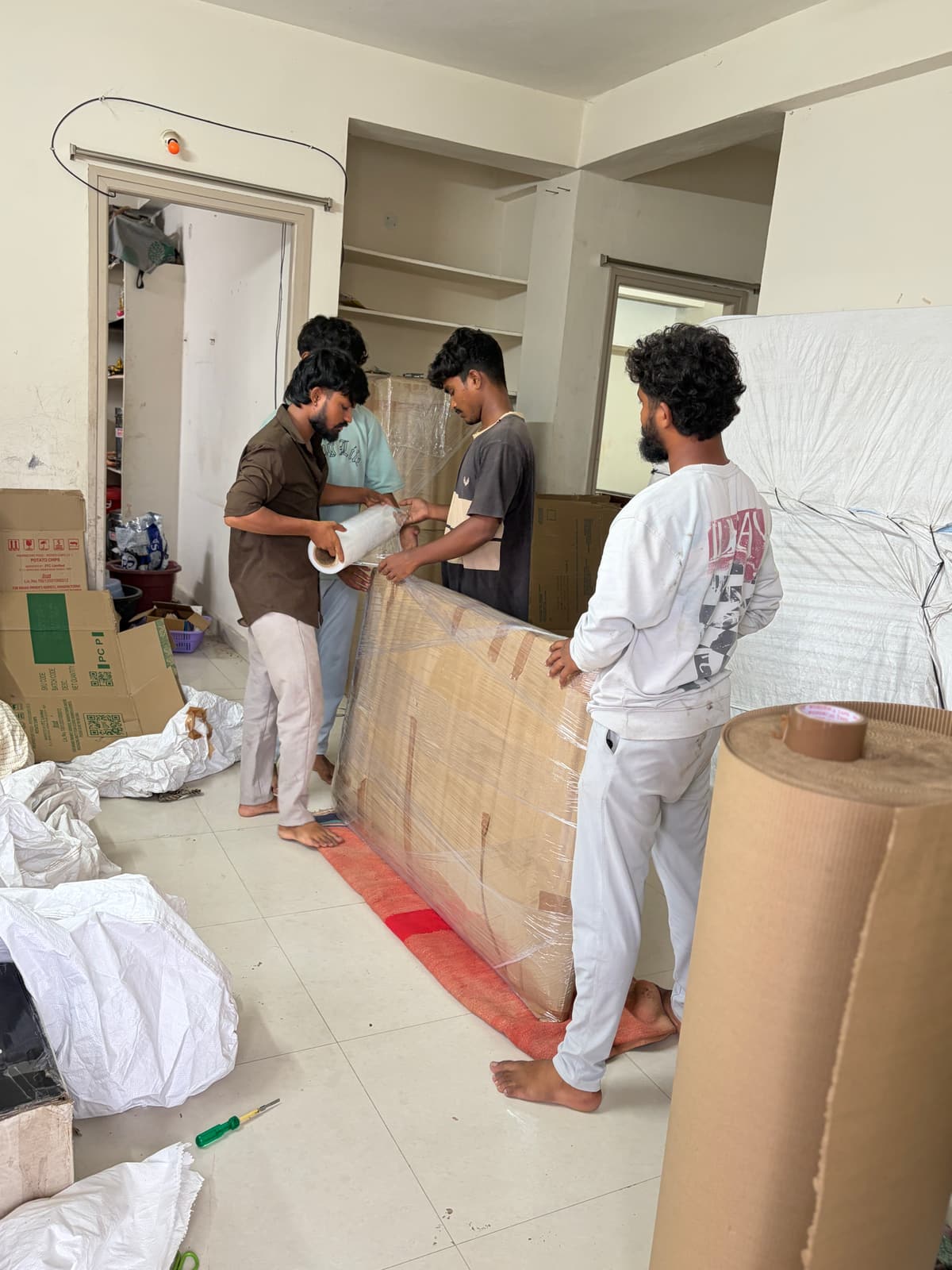 Dwaraka crew stretch-wrapping a wardrobe before a house shifting in Sircilla
