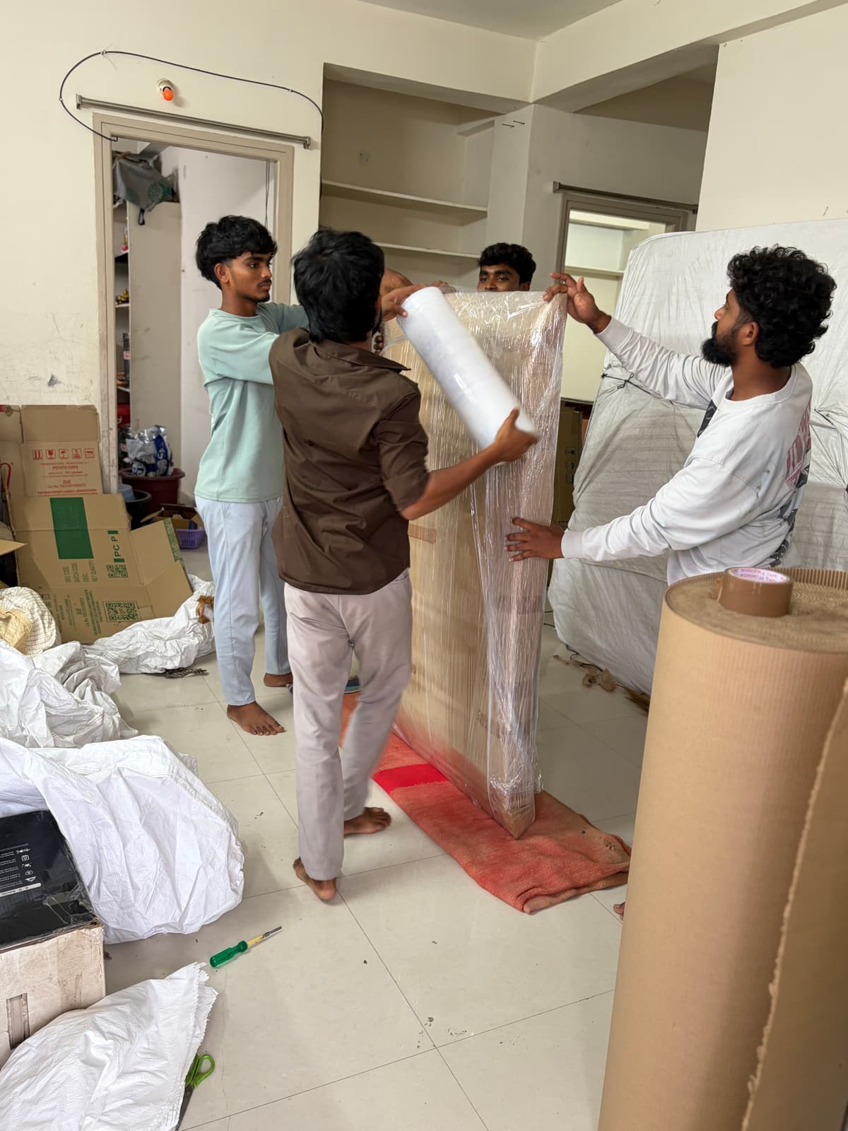 Four-man Dwaraka packing crew wrapping furniture for relocation in Sircilla, Telangana